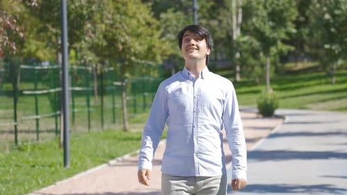 Young Adult Man Walking and Waving in Park