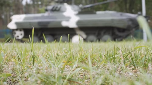 Military Tank Driving Through Grassy Field