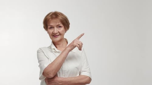 An Elderly Lady Businesswoman or Entrepreneur with a Confident Gaze Points to a Certain Object in