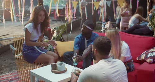 Friends drinking cocktails and talking at summer party