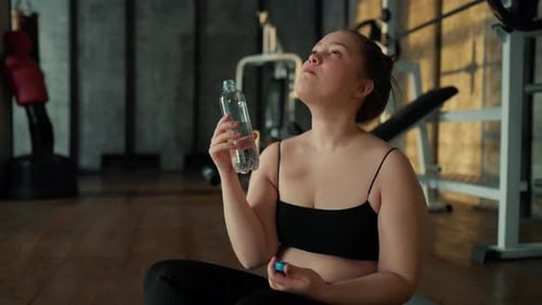 Young Adult Woman Drinking Water in Gym