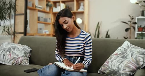 Woman Writing in Notebook on Comfortable Couch