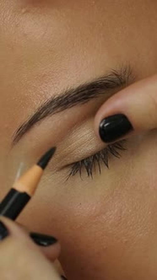 Woman Lying On Couch At Beauty Salon. Cosmetologist making eyeliner permanent make up