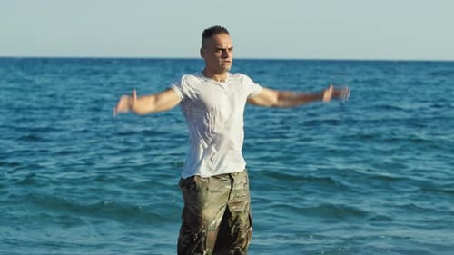Muscular Man Doing Jumping Jacks on the Beach