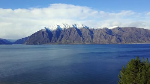 Aerial video of a Van driving on a Coastal road with green paddocks, then panning to the blue ocean,