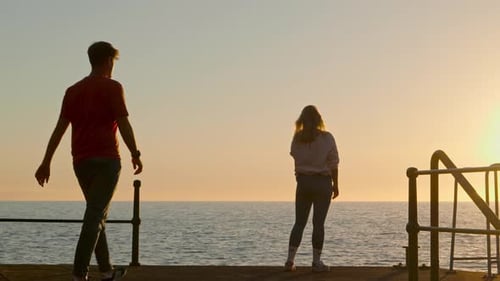 Loving couple on a romantic vacation, embrace and kiss by the sea at sunset