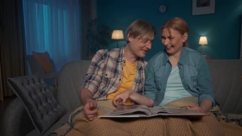 Couple Looking at Photo Album on Couch at Night