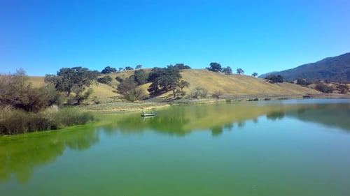 Fishermen On A Boat By Mountainside Lake By Aerial Drone