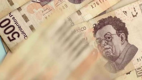 Close-up of many Mexican 500 Peso bills being thrown on table