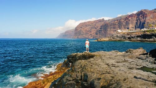 Man Tourist Enjoys Ocean Waters View From Rocky Beach on Volcanic Tenerife Island