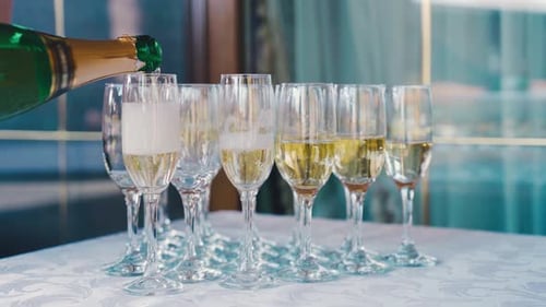 A Waiter Pours Champagne Wine Into Glasses at a Buffet Table Closeup Champagne is Pouring Into a