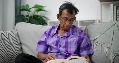 Senior Man Reading a Book on the Couch