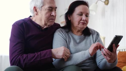 Senior Couple Using Smartphone Together in Bright Home