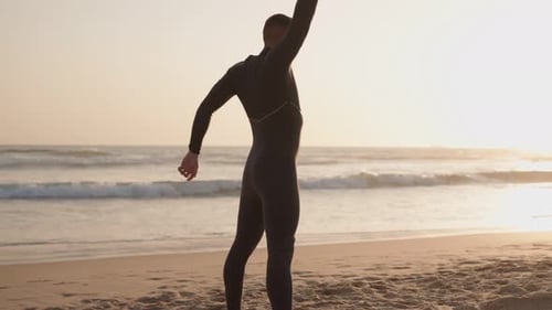 Surfeur qui s'échauffe sur la plage avant le coucher du soleil