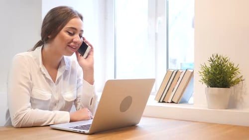 Phone Negotiation By Young Girl Working on Laptop