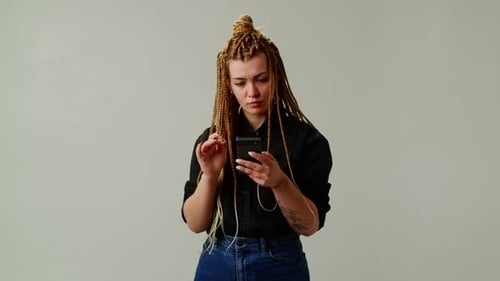 Une fille moderne avec des nattes a appris une nouvelle incroyable sur son téléphone La fille se réjouit de la bonne nouvelle