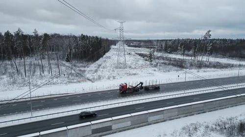 An Aerial View of a Winter Landscape Featuring a Snowy Highway Alongside a Tractor in the