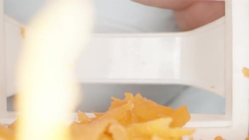 Carrots are crushed on a grater, carrots are poured on the camera. Dolly slider, extreme close-up.