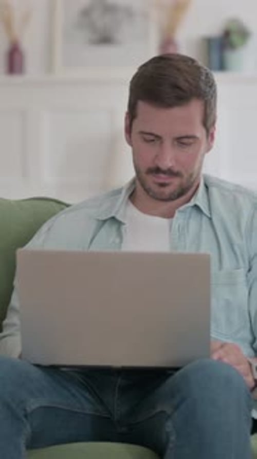 Man Works on Laptop While Sitting on Couch