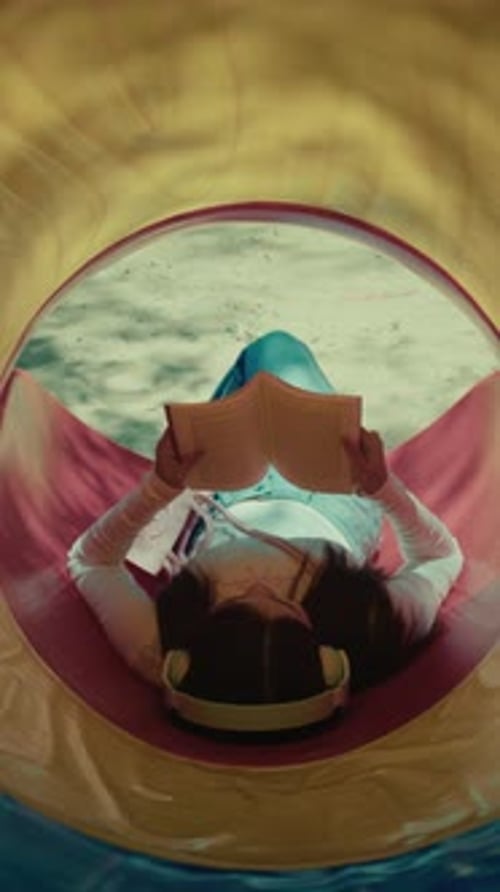 vertical of young asiatic woman reading a book and listening music relaxing during her day off in th