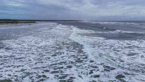 Drone Aerial Footage of Strong Ocean Surf Crashing Near Sandy Coast Under Cloudy Weather