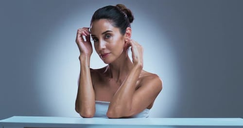 Woman Poses with Hands Near Face in Studio