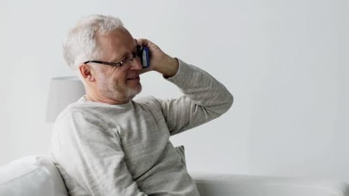 Senior Man Talking on Smartphone Indoors on Couch