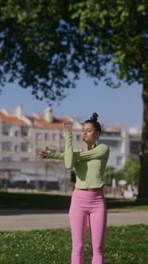 A Woman Engaging in Yoga Practice Amidst the Greenery of a Park on a Bright Sunny Day