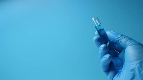 Gloved Hand Holding Test Tube with Blue Liquid