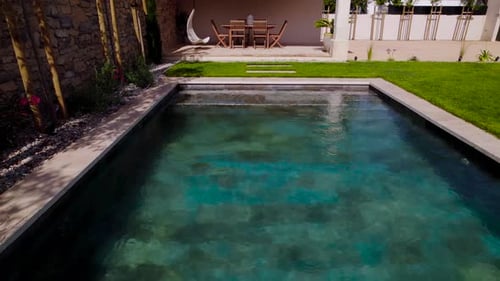Aerial dolly shot revealing a tropical swimming pool in a villa garden