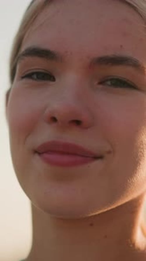 Gros plan de la jeune femme souriante sous la lumière chaude du soleil avec fond vert naturel