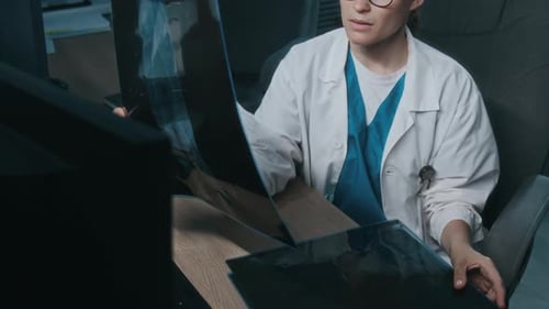 Doctor Reviews X-Rays at Desk in Hospital Office