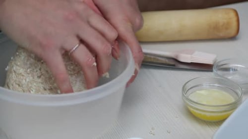 Zubereitung von Zimtstangen. Eine Frau rührt einen Teigklumpen um. Die Zutaten liegen auf dem Tisch.