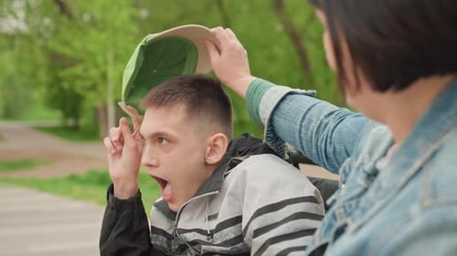 Teenage Boy in Wheelchair Receives Help With Cap