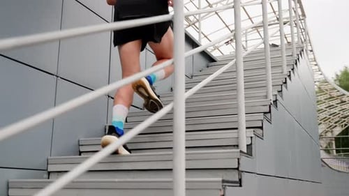 A Man Runs Down a Gray Staircase Side View Wide Shot
