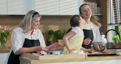 Glückliche blonde Mutter mittleren Alters mit Töchtern beim Backen Kochen Hausgemachte Hauskekse