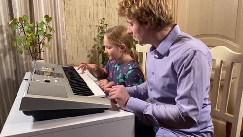 Child Plays Piano with Adult Guidance