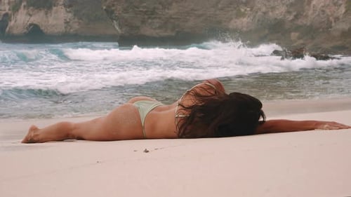 Woman in Bikini Lying on the Sandy Beach Near the Ocean Enjoying
