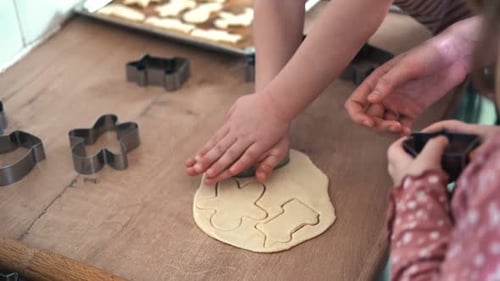 3Yearold Girl Standing on a Stool Rolling Out Cookie Dough with a Wooden Rolling Pin on the Kitchen