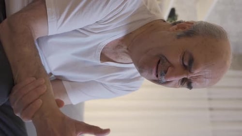 Senior Man Massages Aching Wrist Indoors