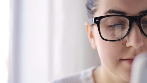 Woman with glasses looking at her cellphone screen