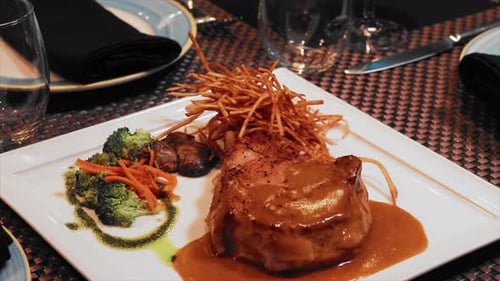 Close up dish of filet of mignon with broccoli and hash browns on white plate. On a black table of a