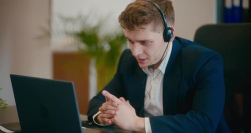 Young Adult Talking on Headset at Office Desk