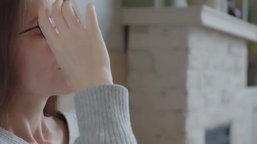 Woman Looks At Smartphone Indoors Then Removes Glasses