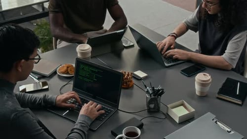 High Angle of Developers Working on Tablet and Laptops at Pushed Together Desks