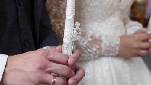 S 115. Die Braut und der Bräutigam halten Kerzen bei einer kirchlichen Hochzeit in der Hand.