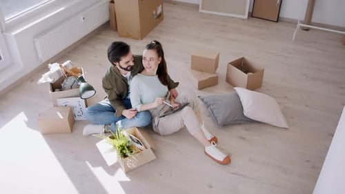Loving Couple Sits on Floor Planning New Home