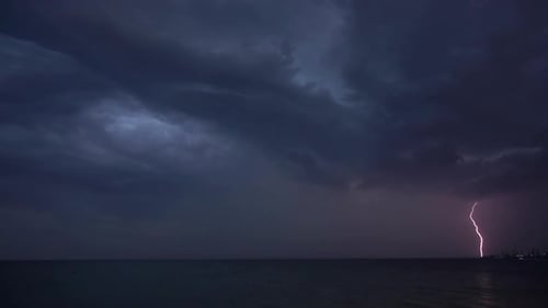 Flashes of lightning in the night sky among thunderclouds.