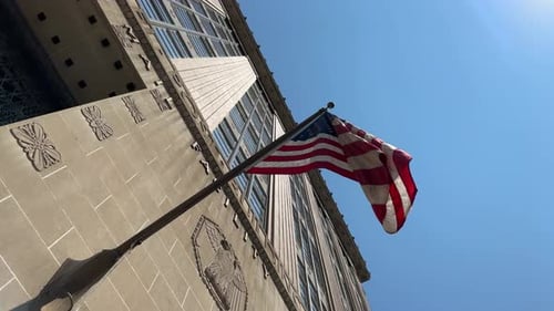 American Flag Waving Next to Building on Sunny Day