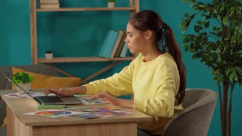 Mittlere Aufnahme, die eine Frau fotografiert, die in ihrem Heimbüro arbeitet. Junge Designerin schaut sich einen Vergleich an